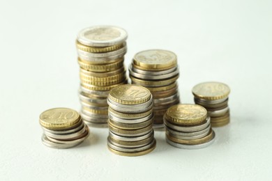 Photo of Stacks of euro coins on white textured table, closeup