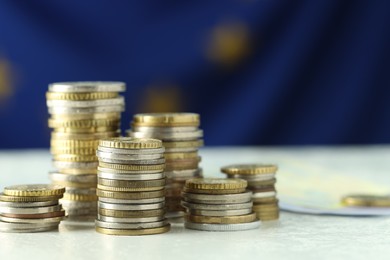 Photo of Stacks of euro coins on white table, closeup