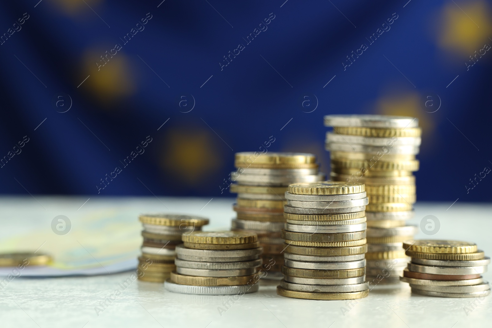 Photo of Stacks of euro coins on white table, closeup