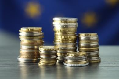 Photo of Stacks of euro coins on grey textured table, closeup