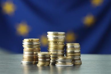 Photo of Stacks of euro coins on grey textured table, closeup