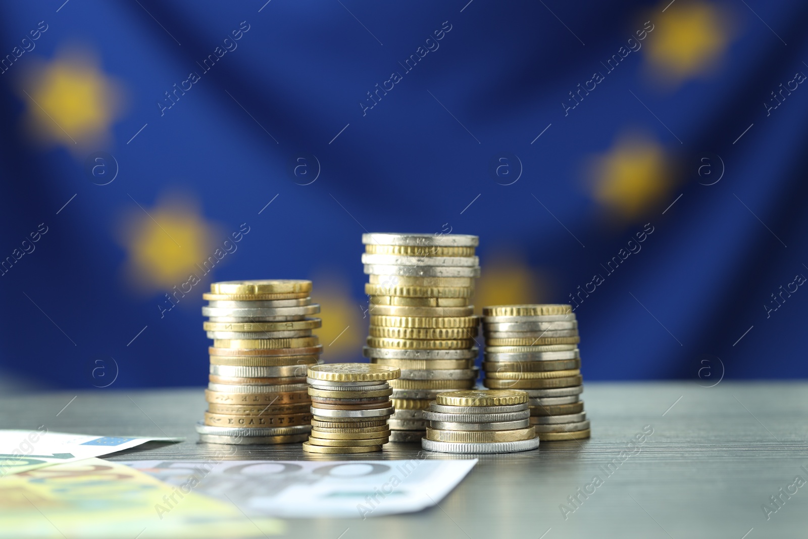 Photo of Stacks of coins and euro banknotes on grey table