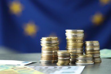 Photo of Stacks of coins and euro banknotes on grey table, closeup