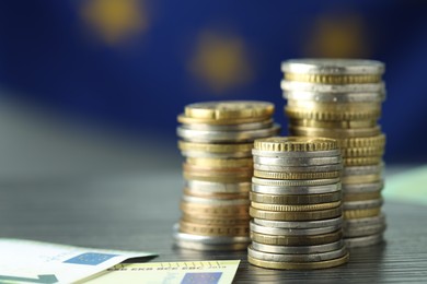 Photo of Stacks of coins and euro banknotes on grey textured table, closeup