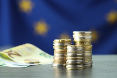 Photo of Stacks of coins and euro banknotes on grey textured table, closeup