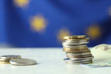 Photo of Stack of coins and euro banknotes on white table, closeup