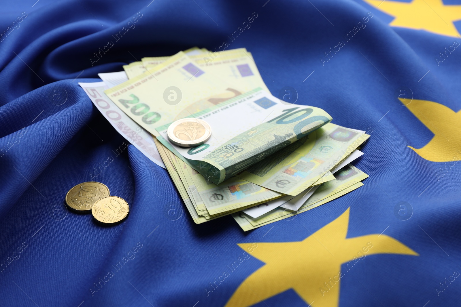 Photo of Euro banknotes and coins on European Union flag, closeup