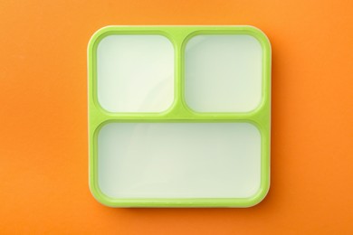 Photo of One lunch box on orange background, top view