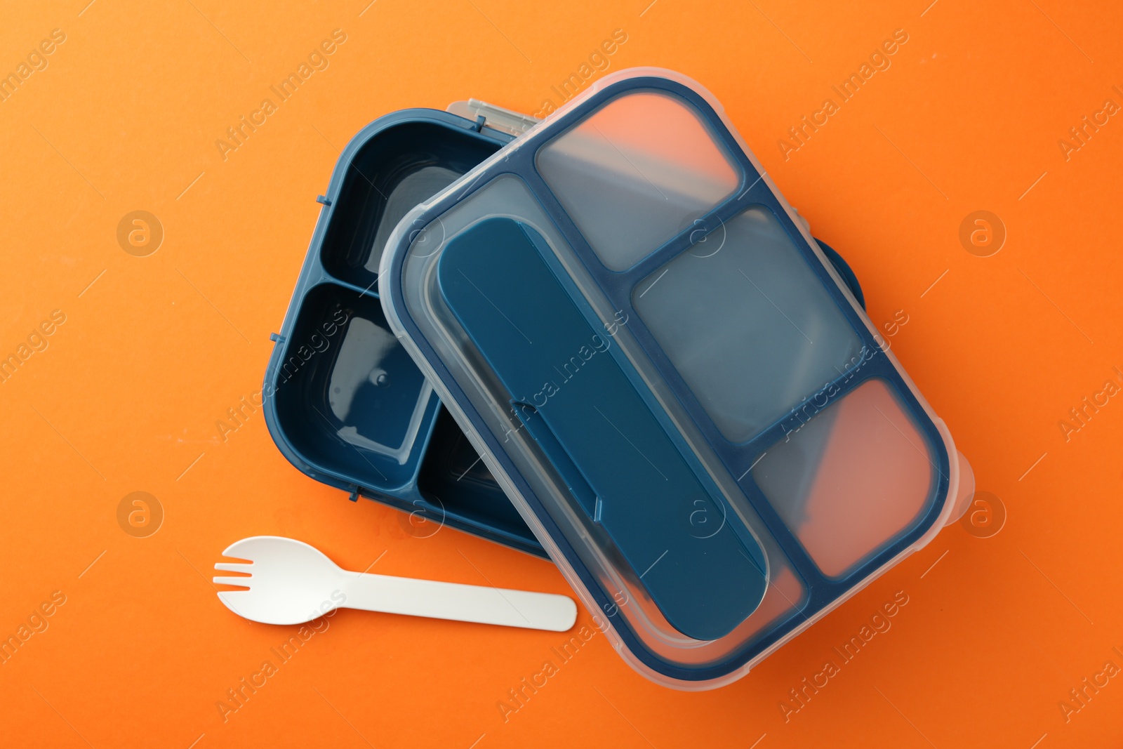 Photo of Empty lunch box and fork on orange background, flat lay