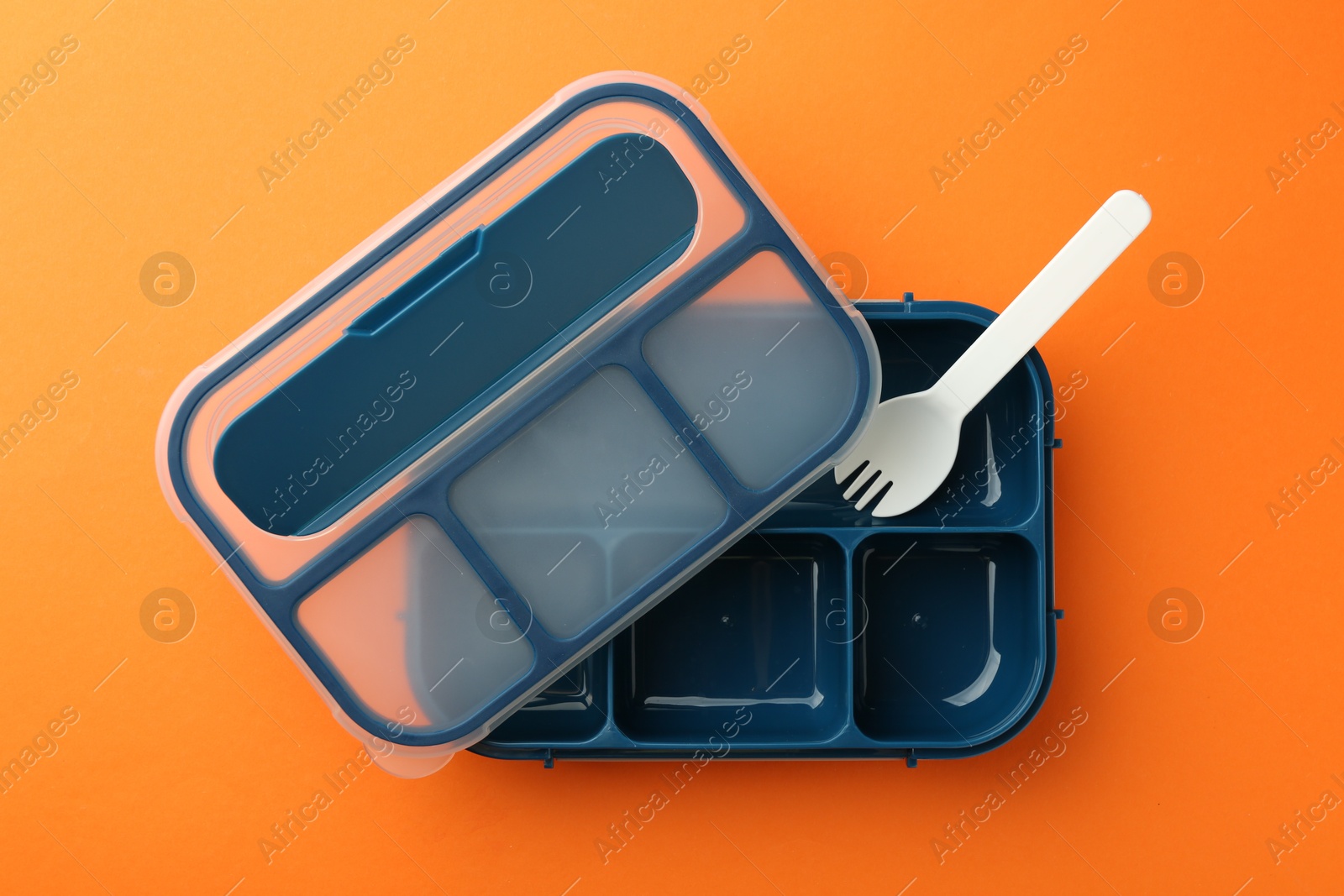 Photo of Empty lunch box and fork on orange background, flat lay