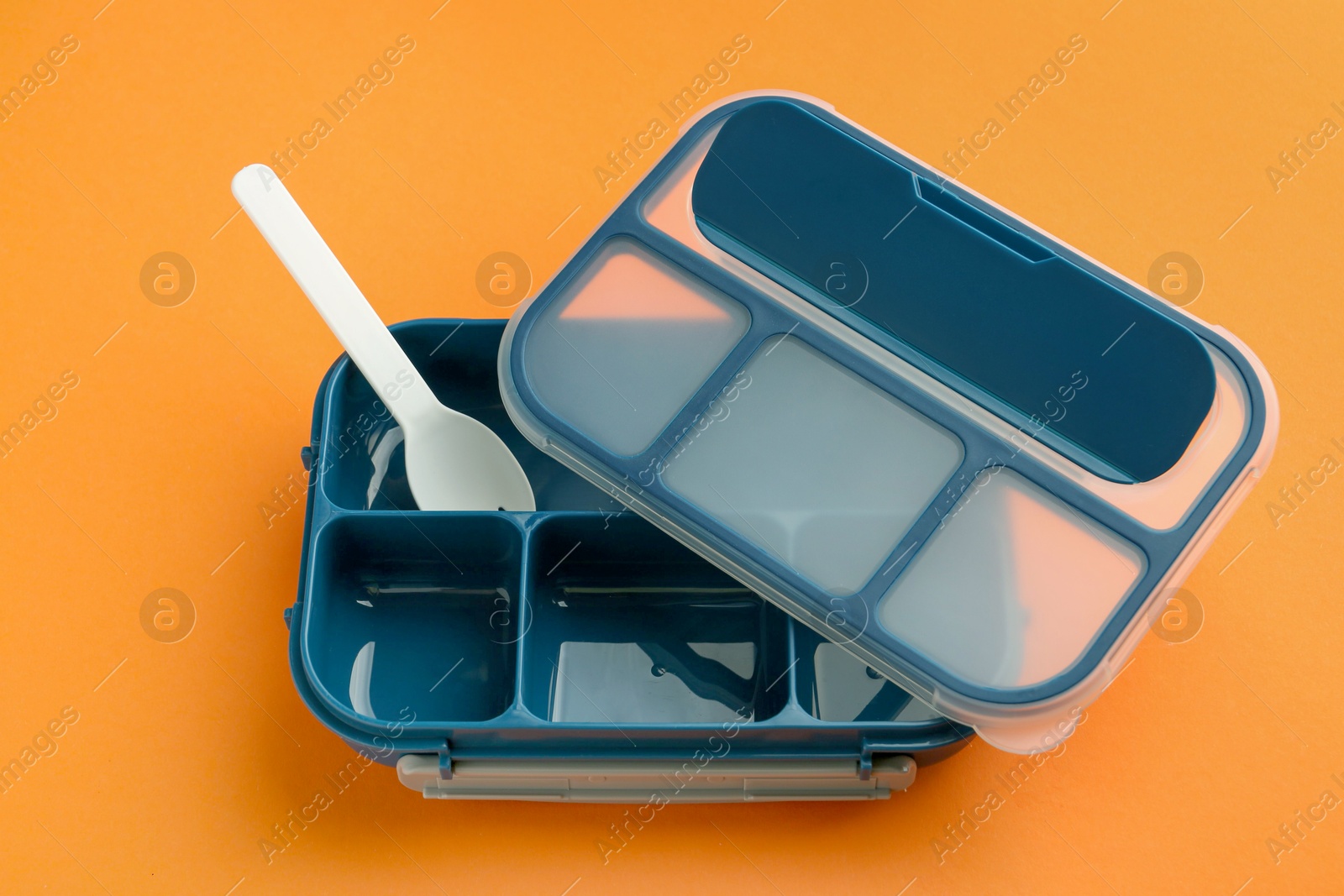 Photo of Empty lunch box and fork on orange background, above view