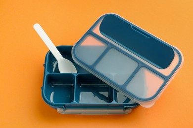 Photo of Empty lunch box and fork on orange background, above view