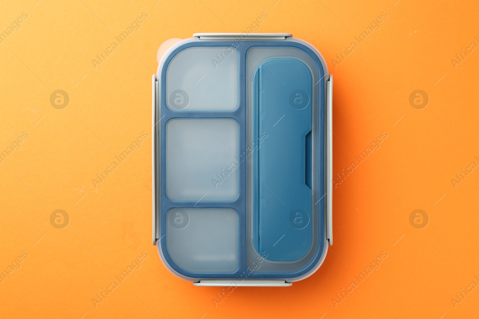 Photo of One lunch box on orange background, top view