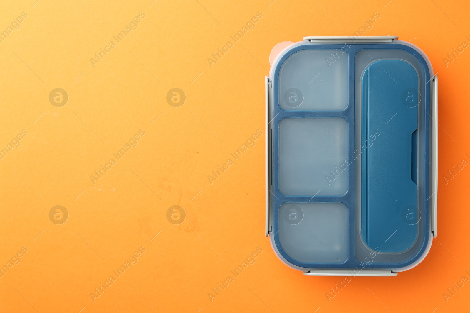 Photo of One lunch box on orange background, top view. Space for text