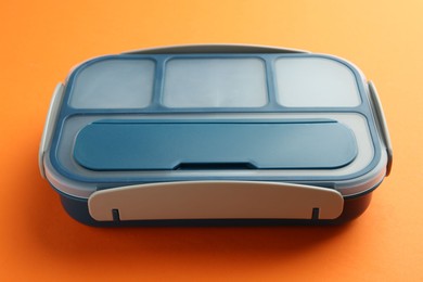 Photo of One bright lunch box on orange background