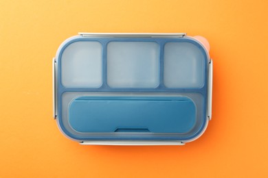 Photo of One lunch box on orange background, top view