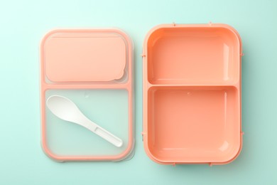 Photo of Empty lunch box with spoon on light blue background, flat lay