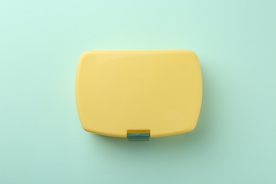 One yellow lunch box on light blue background, top view