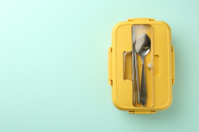 Photo of One lunch box with cutlery on light blue background, top view. Space for text