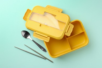 Photo of One empty lunch box with cutlery on light blue background, flat lay