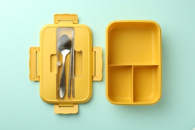 Photo of One empty lunch box with cutlery on light blue background, flat lay