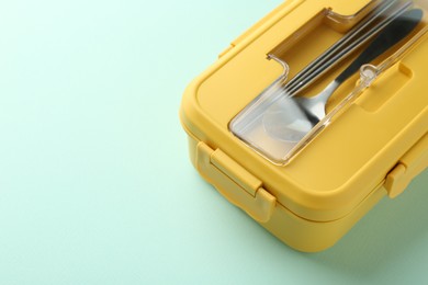 Photo of One lunch box with cutlery on light blue background. Space for text