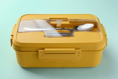 Photo of One lunch box with cutlery on light blue background