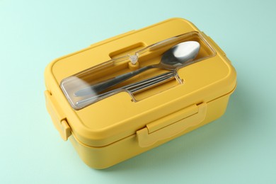 Photo of One lunch box with cutlery on light blue background