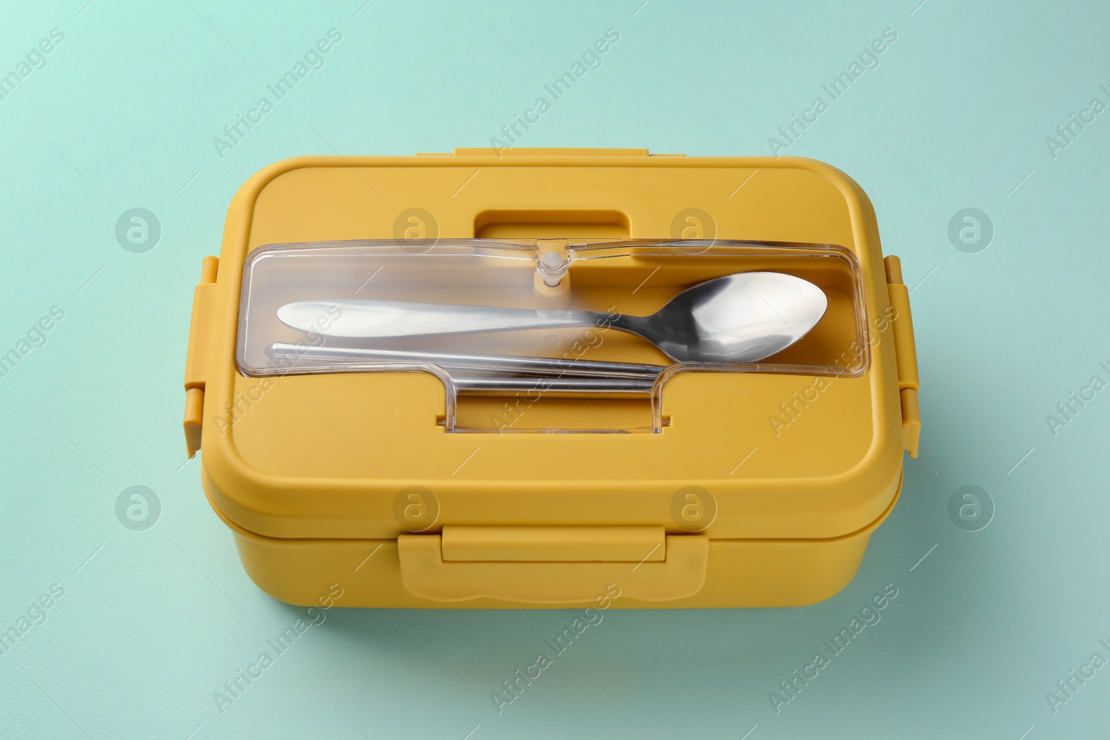 Photo of One lunch box with cutlery on light blue background