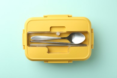 Photo of One lunch box with cutlery on light blue background, top view