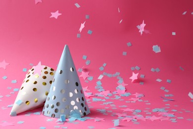 Beautiful confetti falling on party hats against pink background. Space for text