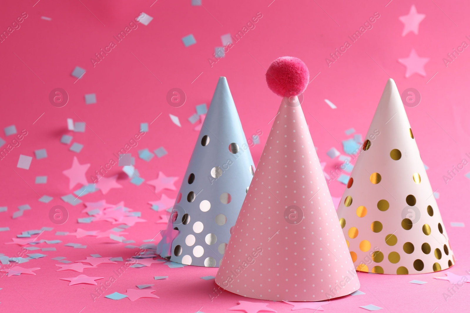 Photo of Beautiful confetti and party hats on pink background, closeup. Space for text