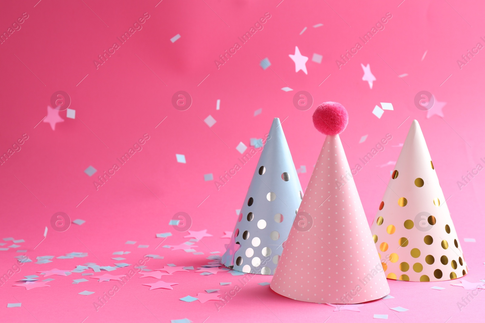 Photo of Beautiful confetti and party hats on pink background. Space for text