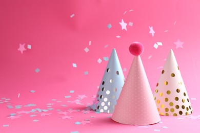 Photo of Beautiful confetti and party hats on pink background. Space for text