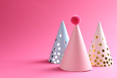 Beautiful party hats on pink background. Space for text