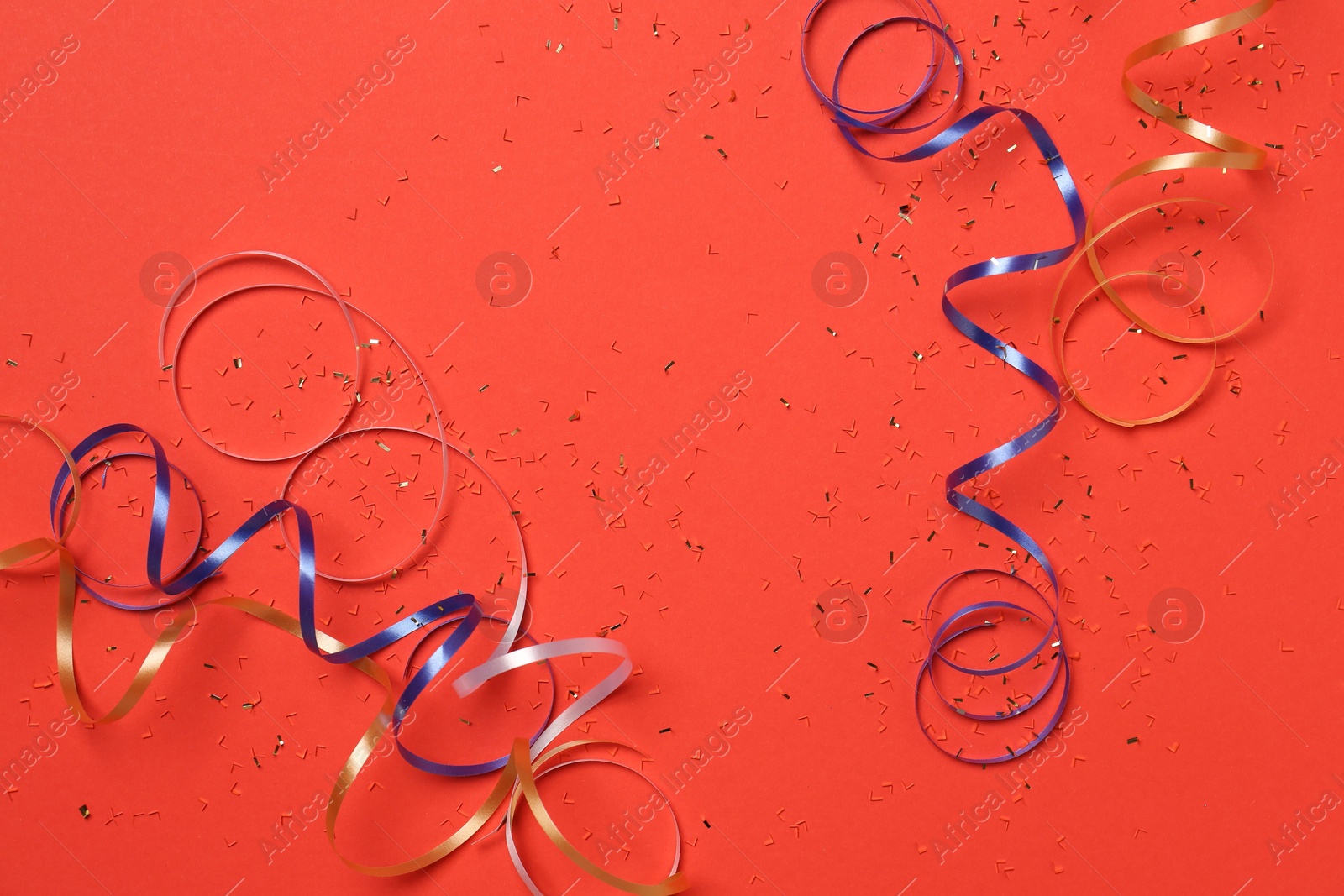 Photo of Shiny confetti and party streamers on red background, flat lay