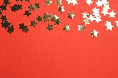 Photo of Shiny confetti on red background, flat lay. Space for text