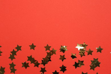 Photo of Shiny confetti on red background, flat lay. Space for text