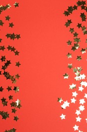 Shiny confetti on red background, flat lay. Space for text