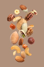 Pecan and other nuts in air on dark beige background