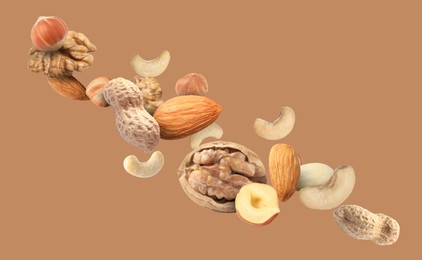 Mix of nuts in air on dark beige background