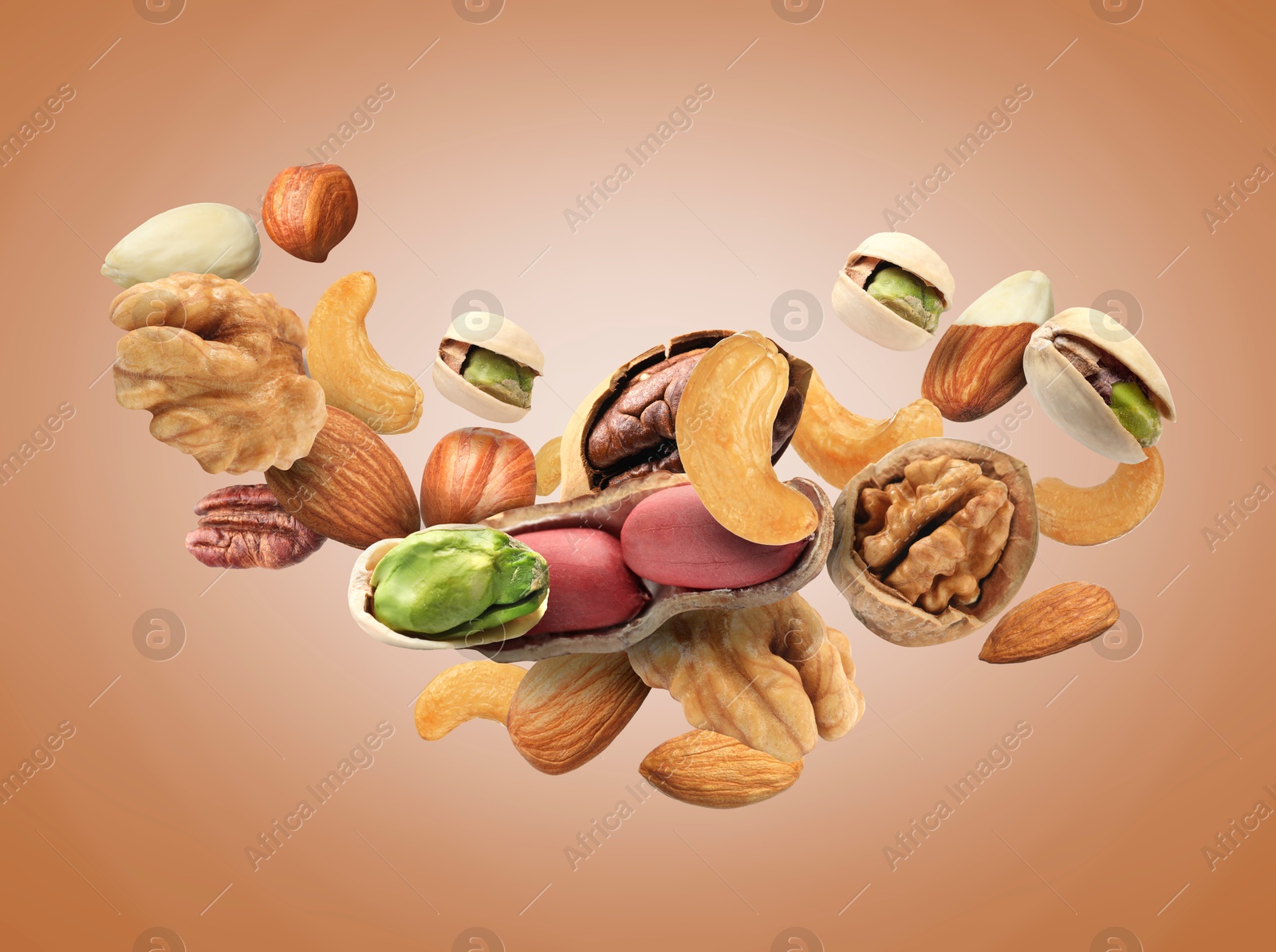 Image of Pecan and other nuts in air on light brown background