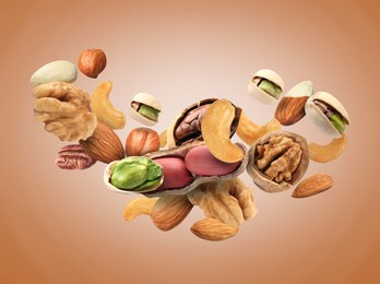 Pecan and other nuts in air on light brown background