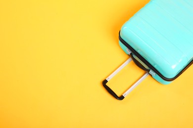 One turquoise suitcase on yellow background, above view. Space for text