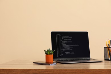 Photo of Programmer's workplace. Modern laptop with unfinished code on desk