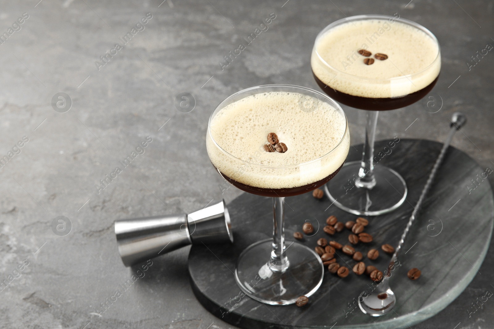 Photo of Espresso Martini cocktail in glasses and beans on grey textured table