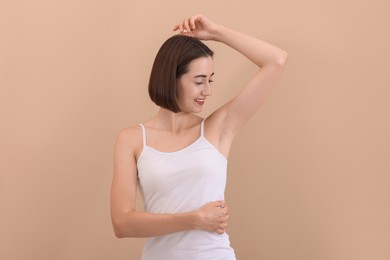 Photo of Smiling woman after using deodorant on beige background