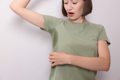 Photo of Emotional woman in t-shirt before using deodorant on white background, closeup