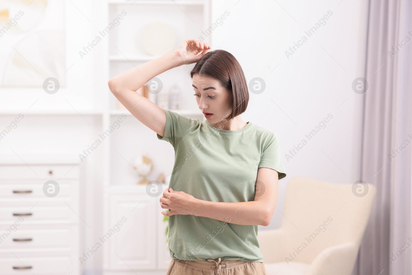 Photo of Emotional woman in t-shirt before using deodorant at home