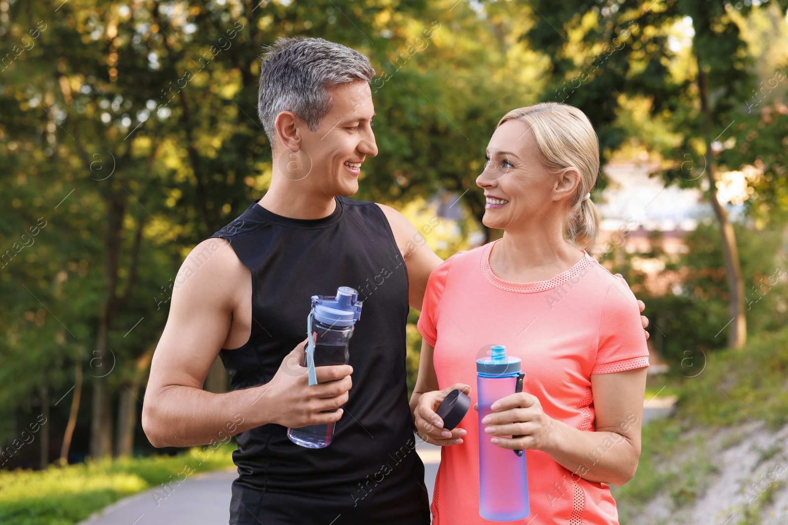 Photo of Happy couple with bottles of water in park